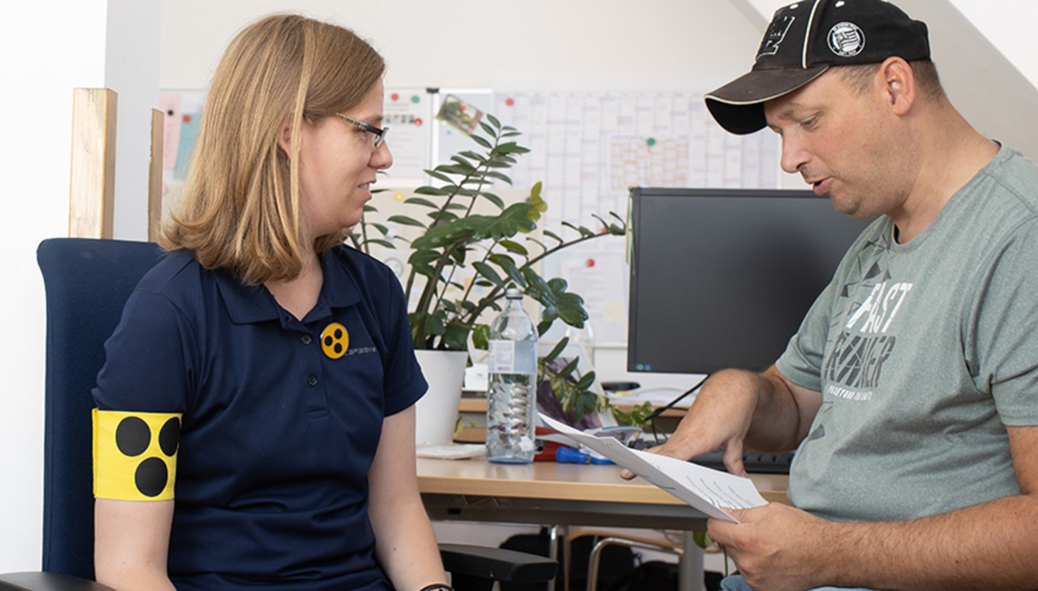 Eine blinde Frau und ein Mann mit Lernschwierigkeiten an einem Schreibtisch mit Computer.