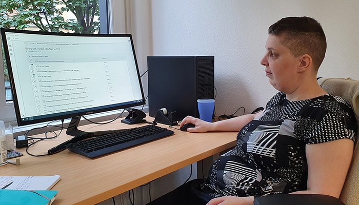 Junge Frau sitzt am Schreibtisch vor dem Computer