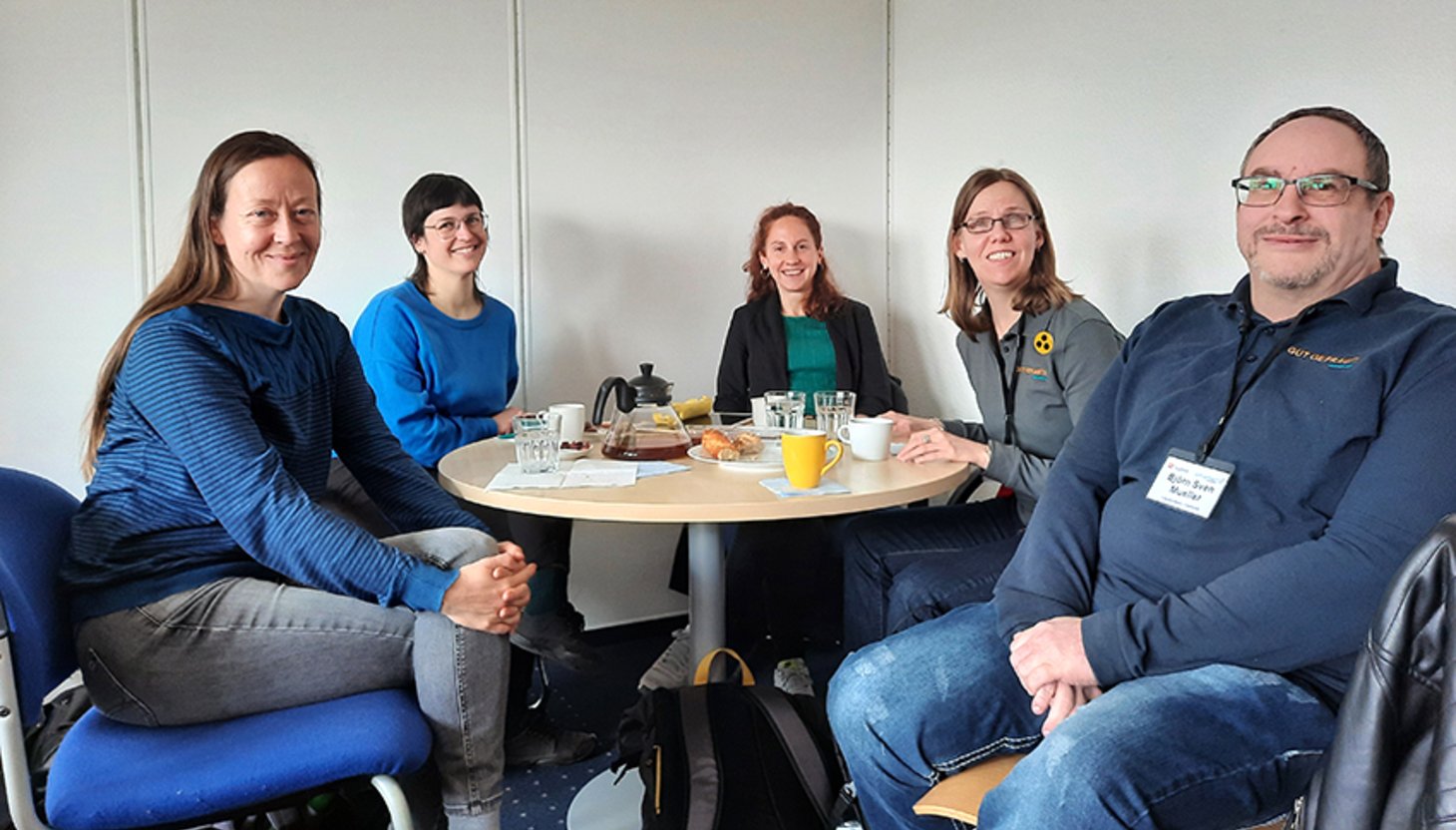 4 Frauen und ein Mann sitzen an einem runden Tisch.