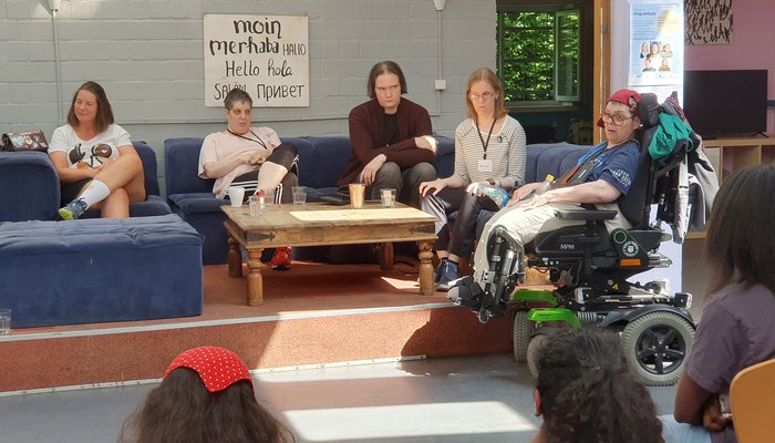 5 Männer und Frauen mit Behinderung auf einer Sitzgruppe