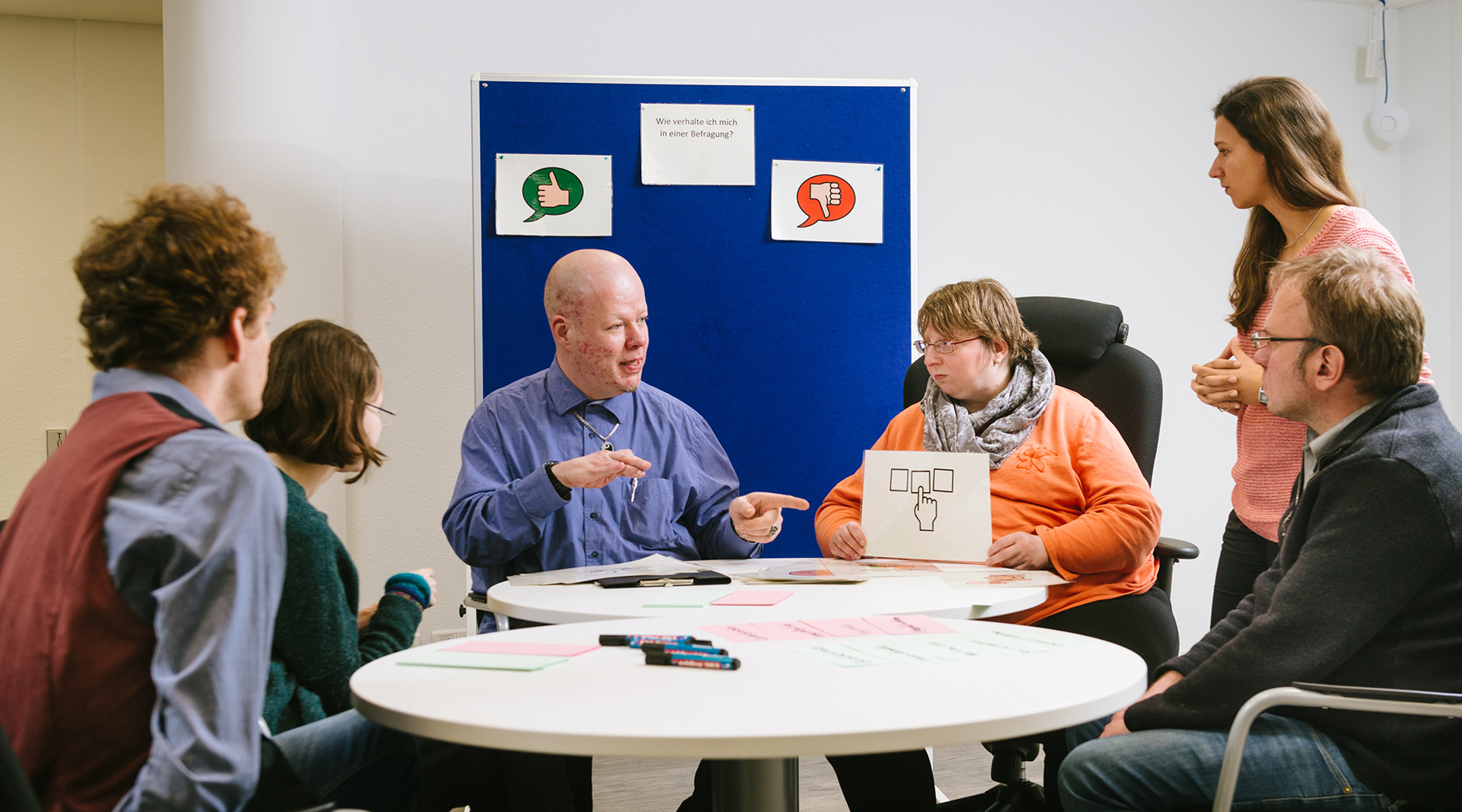 2 junge Frauen und 3 junge Männer mit Behinderungen diskutieren bei einer Ausbildungsstunde mit der Ausbilderin von GUT GEFRAGT.